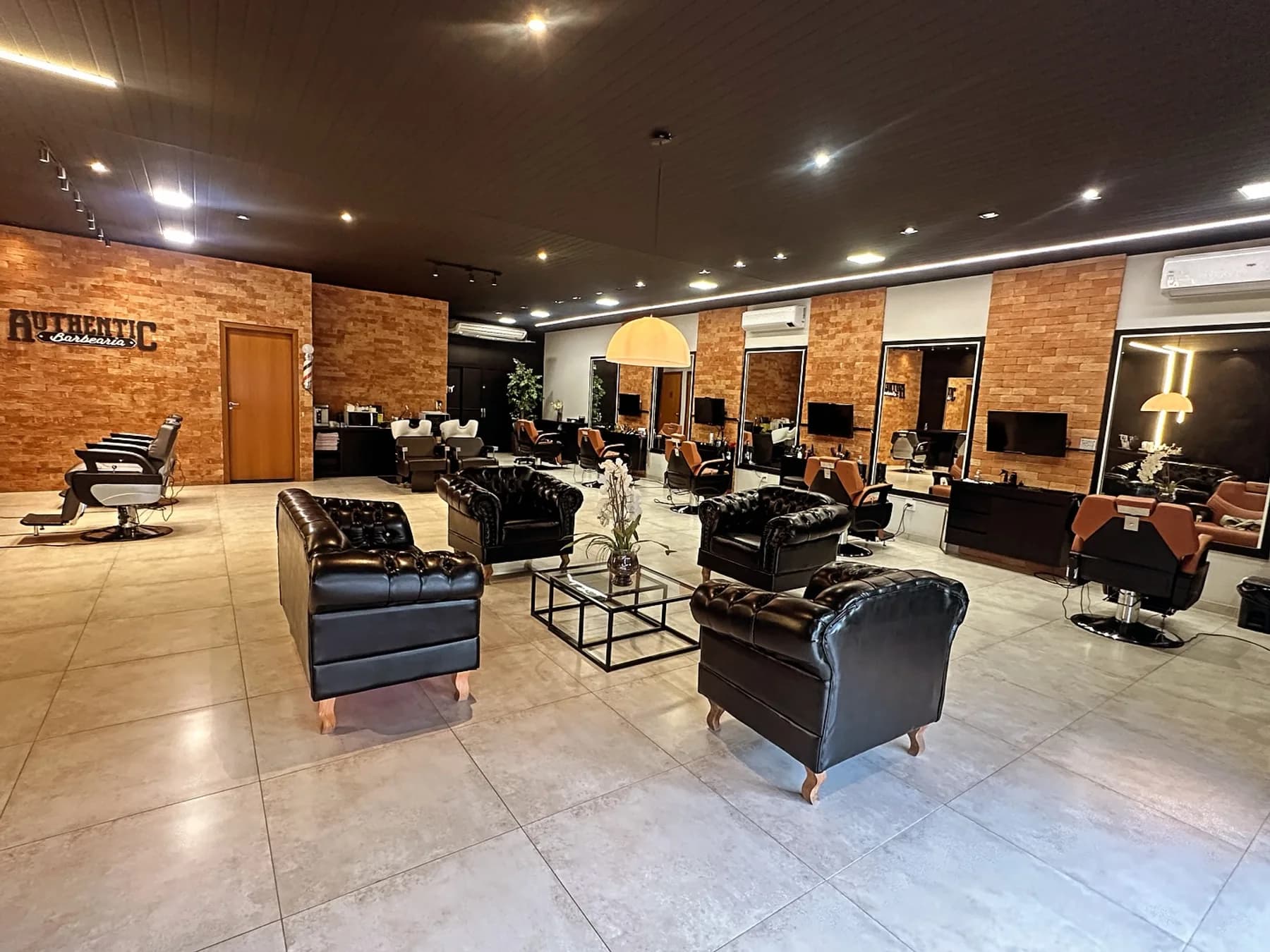 Vista ampla do salão e da área de espera da Authentic Barbearia